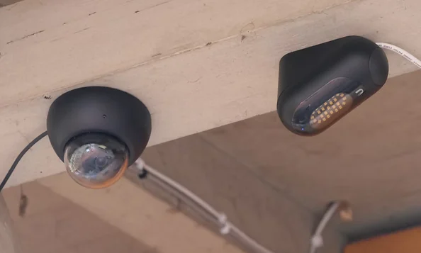 Kuppelkamera und Scheinwerfer mit LED-Licht an einem Dachvorsprung